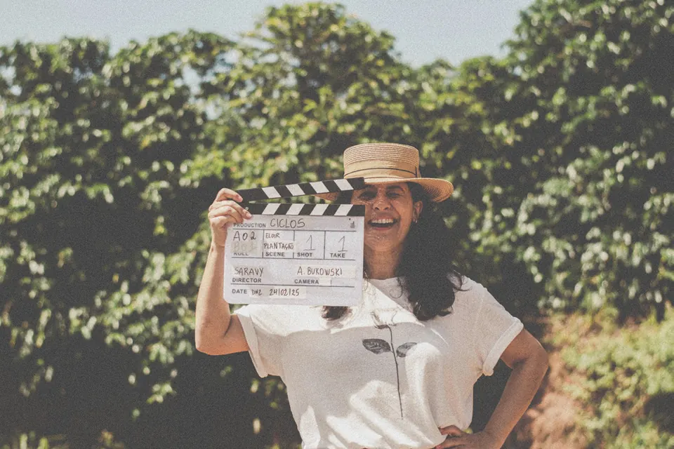 Nina Ribas sorrindo com a claquete do filme Ciclos na lavoura